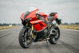 Aprilia RS 125 rouge garée sur circuit asphalte vue 3/4 avant, mise en valeur des carénages aérodynamiques et du pot d'échappement