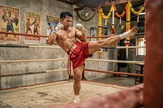 Boxeur thaï en plein entraînement exécutant un teep dans un gymnase de Muay Thai authentique en Thaïlande