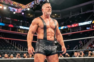 Catcheur professionnel en tenue sombre dans une arène de catch style TNA Impact Zone