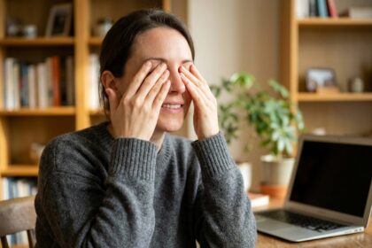 Femme pratiquant un exercice de palming pour soulager la fatigue oculaire à son bureau à domicile