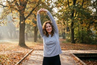 Femme de 45 ans faisant des étirements dans un parc en automne, illustrant une activité physique douce et sans pression après 40 ans