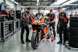 Moto MotoGP dans un garage de stand avec mécaniciens en tenue officielle lors d'une séance d'essais 2026